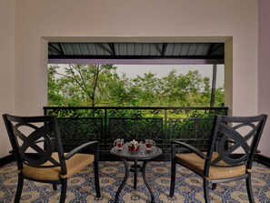 A balcony with two chairs and a table, featuring a view of greenery and trees. - Mayfair Tea Resort Siliguri (Siliguri)