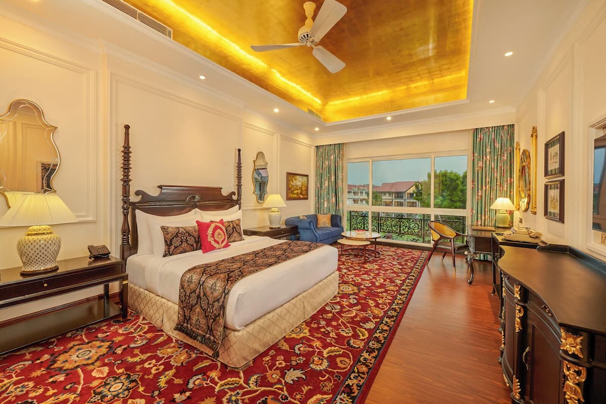 A spacious bedroom with a large bed, a sitting area, and a balcony with a view.