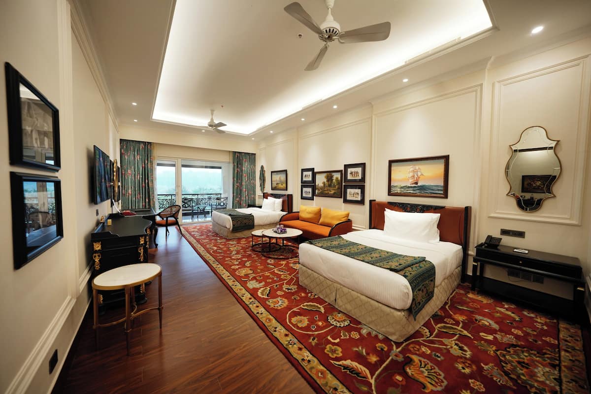 A hotel room with a large bed, a sofa, a desk, and a view of the outdoors.