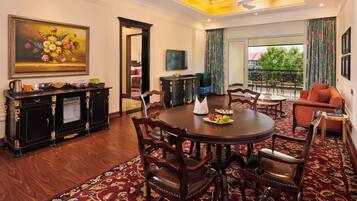 A dining area with a round table, chairs, a buffet, and a painting on the wall.