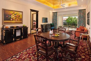 A dining area with a round table, chairs, a buffet, and a painting on the wall.