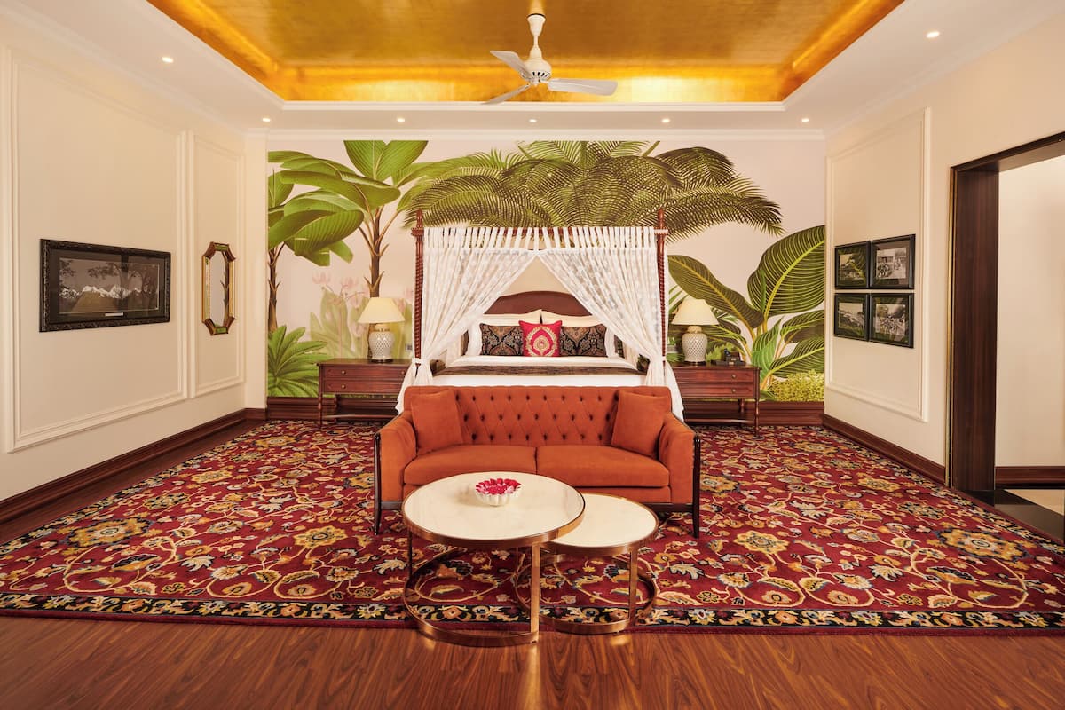 A room with a red sofa, a canopy bed, a round coffee table, and a patterned carpet.