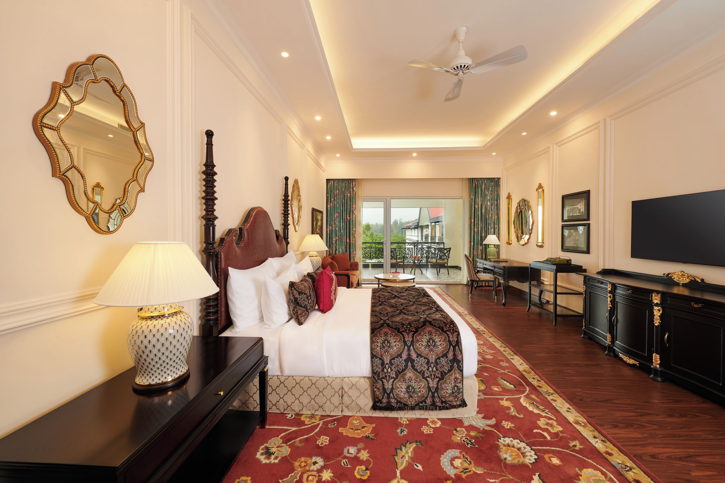 A hotel room with a large bed, a TV, a desk, and a balcony view.