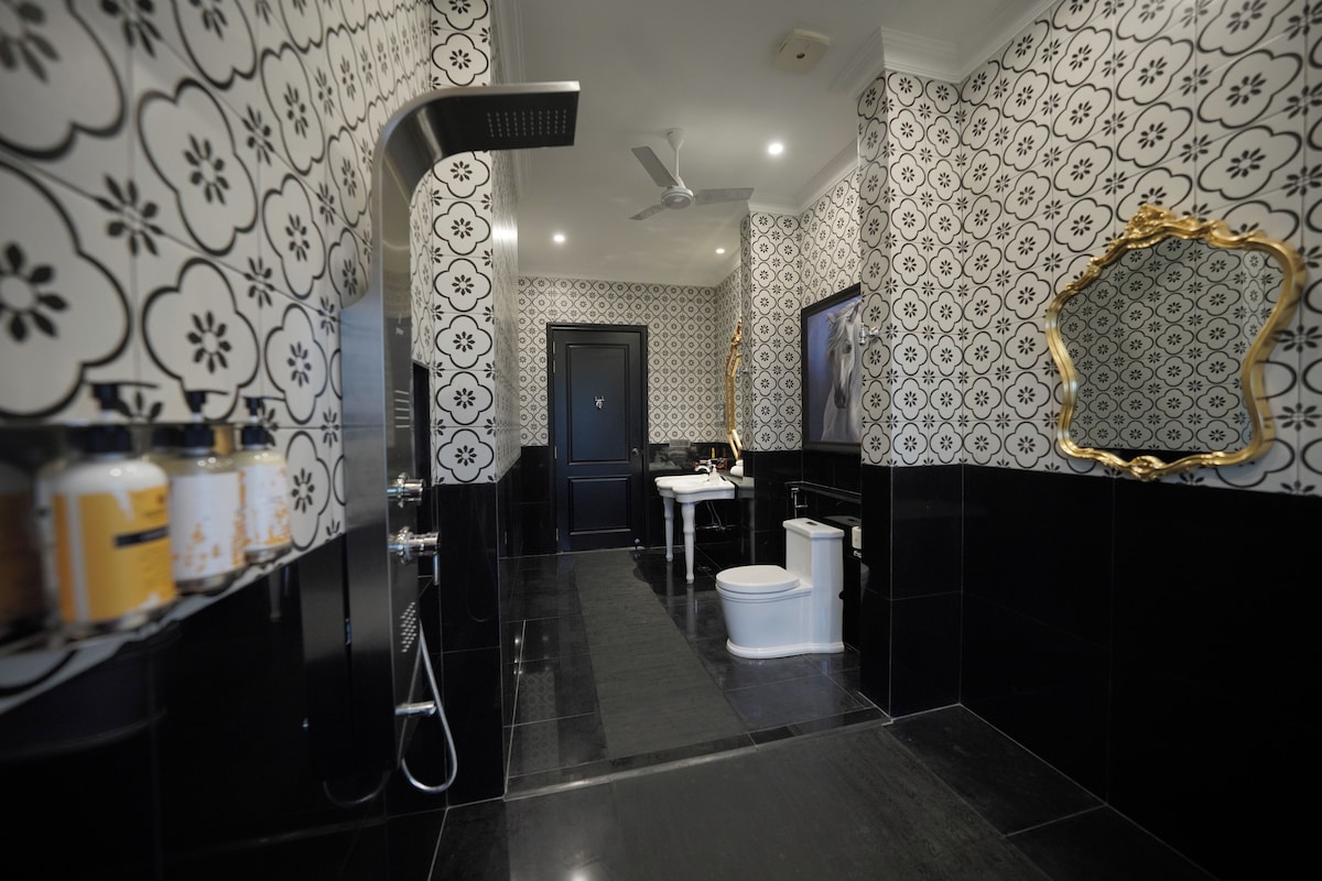 A modern bathroom with black and white patterned walls, a white toilet, a sink, and a shower.