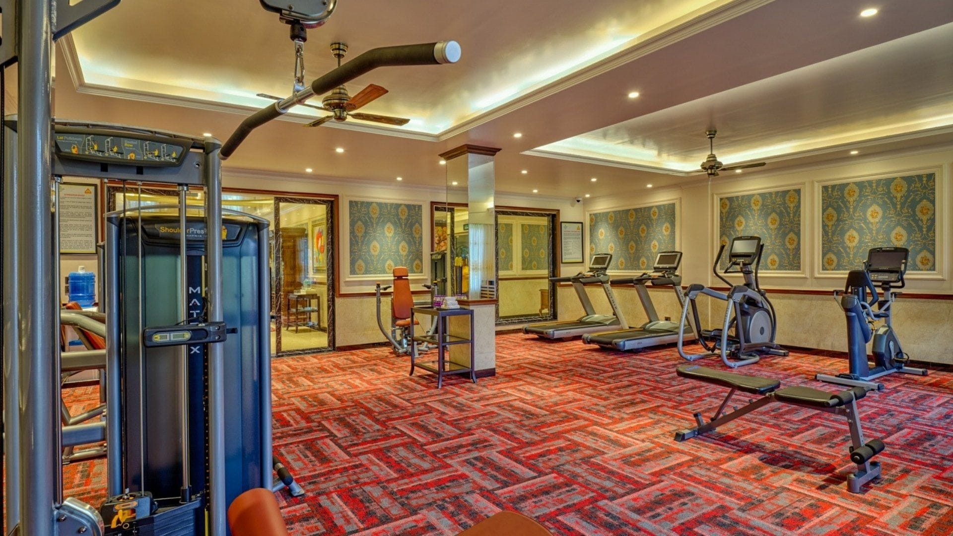 Une salle de sport d’hôtel équipée de matériel d’exercice, d’un fauteuil de massage et d’un distributeur d’eau.
