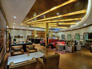 A spacious lounge area with leather seating, a bar, and vintage cars. - Mayfair Tea Resort Siliguri (Siliguri)