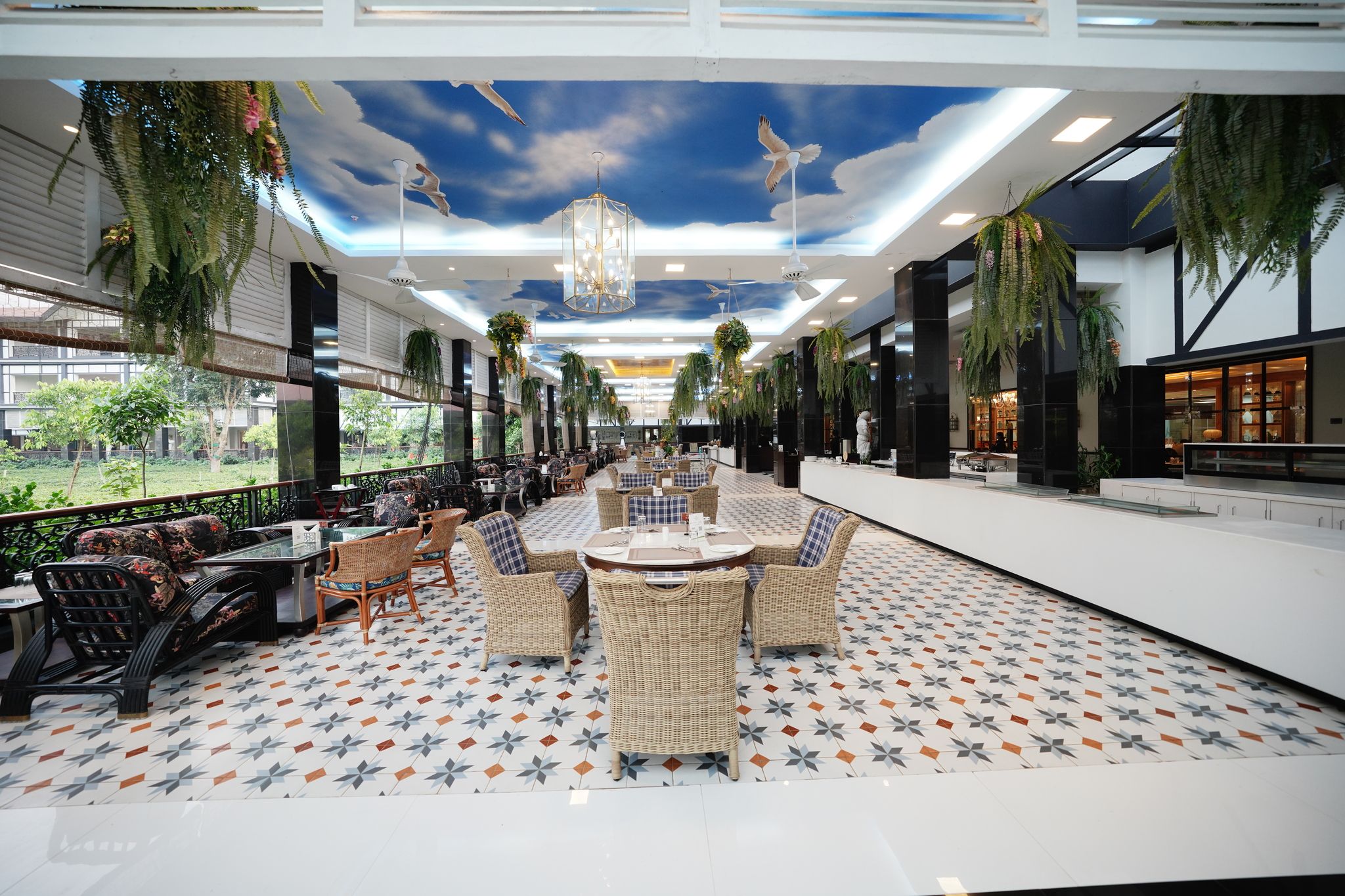 A spacious indoor area with a patterned floor, wicker furniture, and hanging plants.