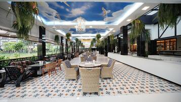 A spacious indoor area with a patterned floor, wicker furniture, and hanging plants.