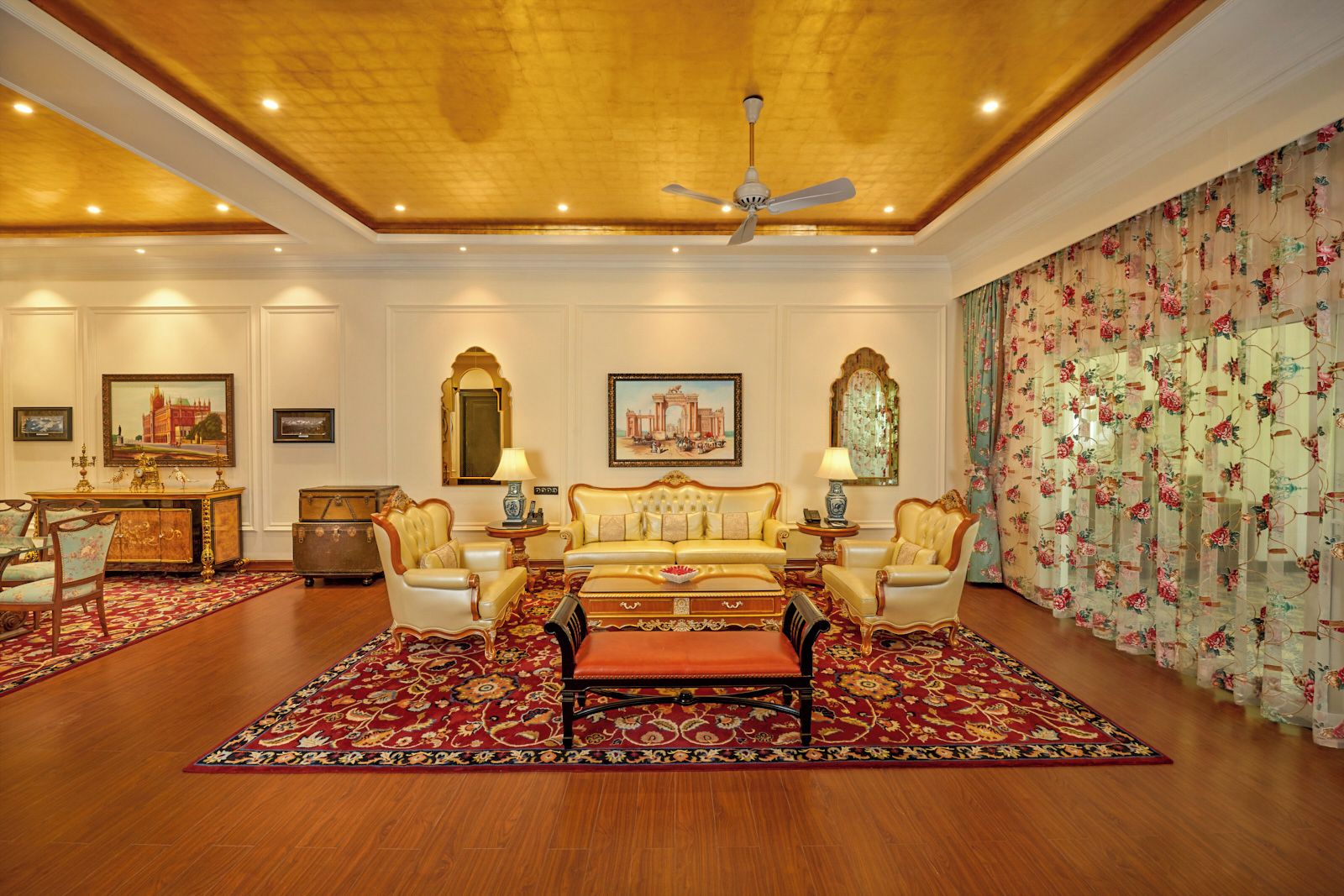 A luxurious room with a large sofa set, a dining area with a wooden cabinet, and a decorative mirror.