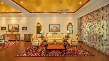 A luxurious room with a large sofa set, a dining area with a wooden cabinet, and a decorative mirror.