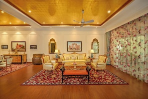 A luxurious room with a large sofa set, a dining area with a wooden cabinet, and a decorative mirror.