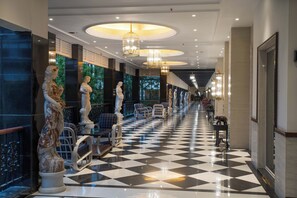 A hotel lobby with a checkered floor, classical statues, and elegant chandeliers. - Mayfair Tea Resort Siliguri (Siliguri)