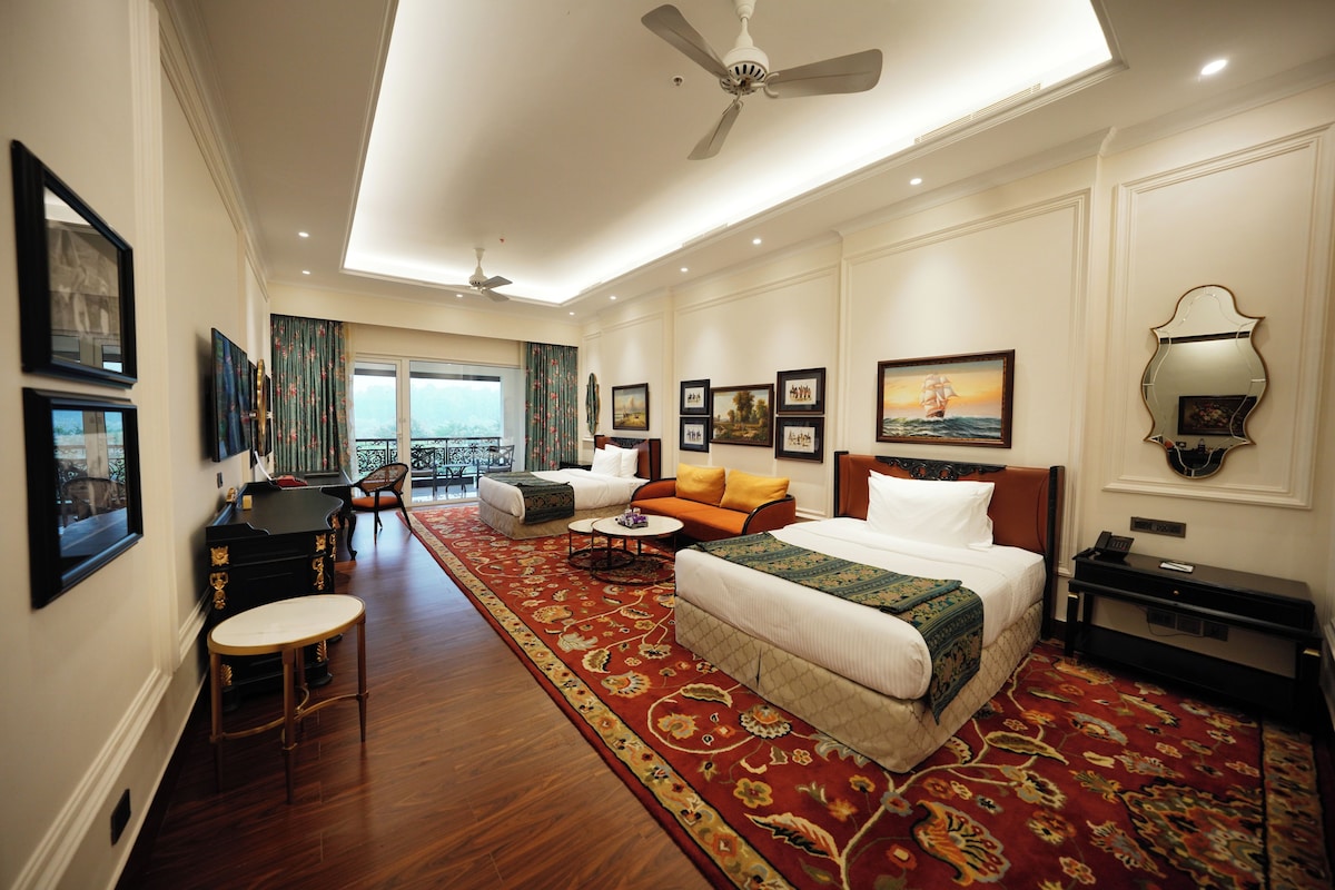 A hotel room with a large bed, a sofa, a desk, and a view of the outdoors.