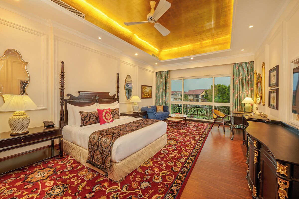 A spacious bedroom with a large bed, a sitting area, and a balcony with a view.