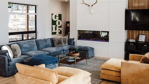 A modern living room with a large sofa, a smaller sofa, a coffee table, and a fireplace with a mounted deer head. - Kestrel House At The Running Y (Klamath Falls)