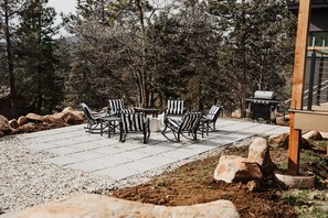 Eine Terrasse im Freien mit einem runden Tisch und sechs gestreiften Stühlen, umgeben von einem Kiesweg und großen Steinen.