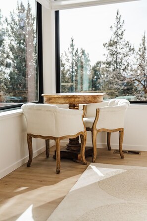 Ein Zimmer mit einem großen Fenster, zwei Polstersesseln, einem Holztisch und einem Teppich auf dem Boden.