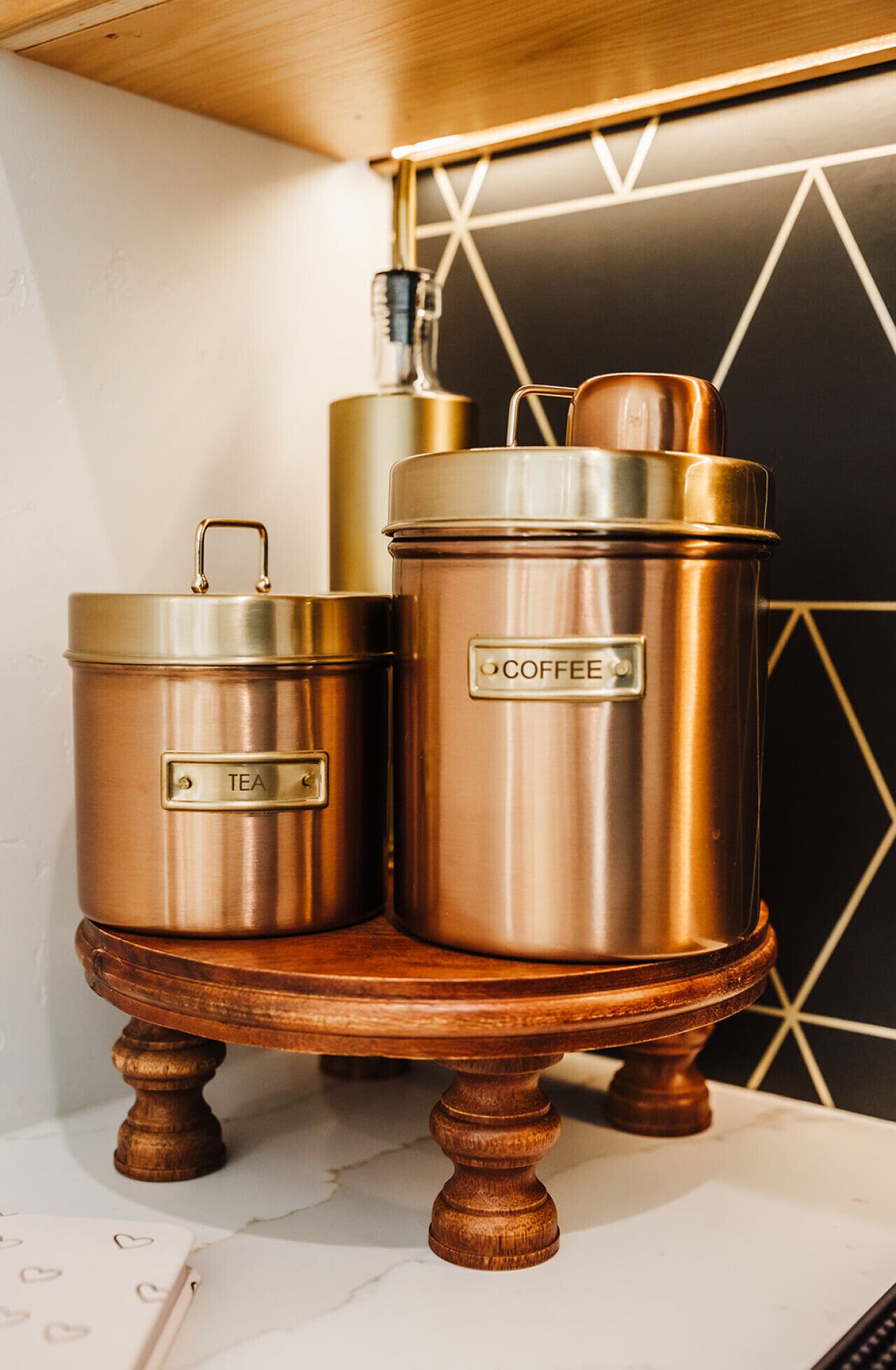 Twee roestvrijstalen containers met de tekst 'THEE' en 'KOFFIE' op een houten standaard.