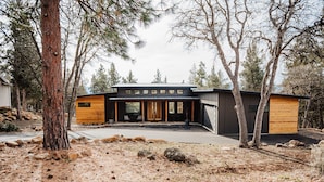A modern two-story house with a garage, large windows, and a covered outdoor seating area. - Kestrel House At The Running Y (Klamath Falls)