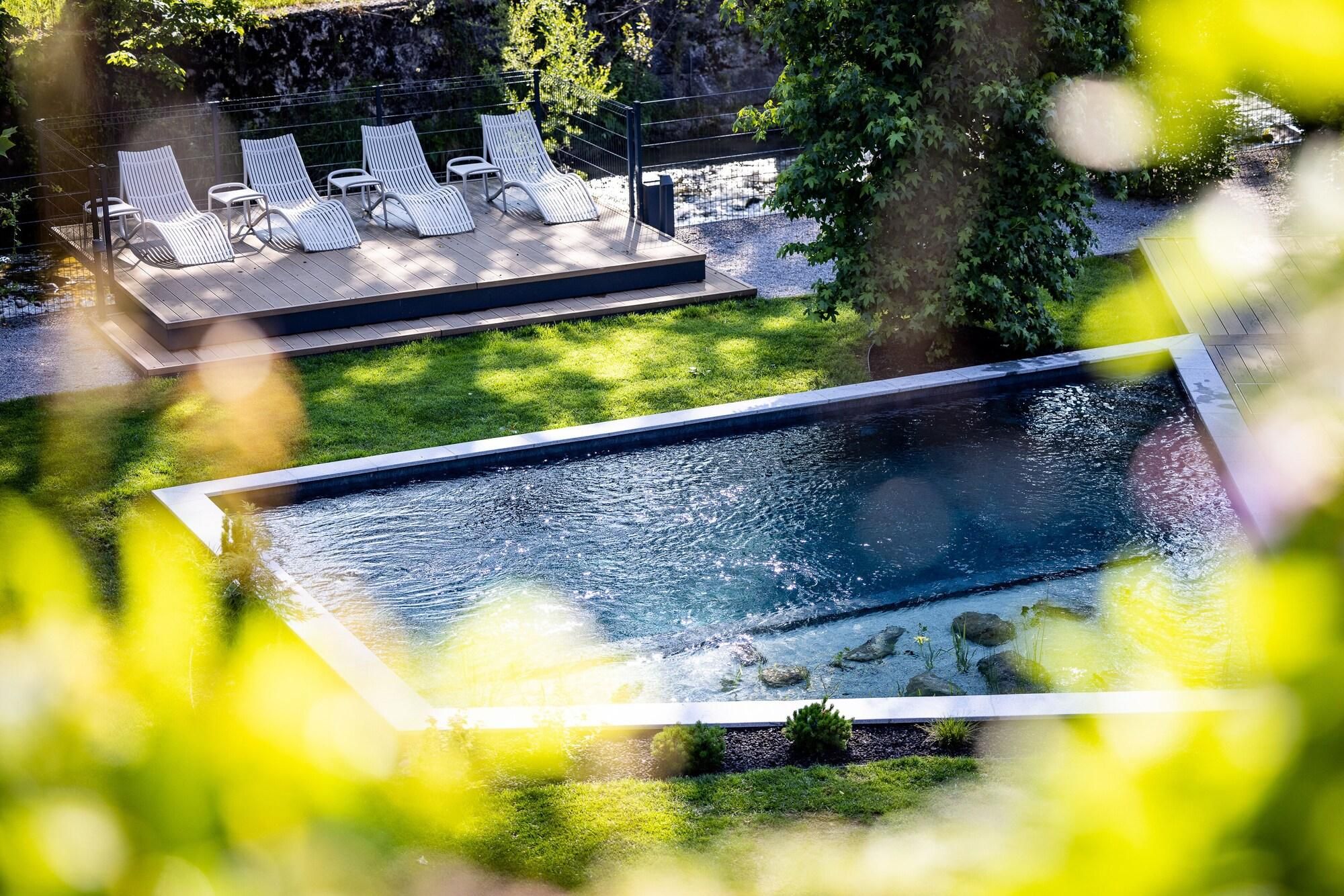 An aerial view of a swimming pool with a deck area featuring lounge chairs and a stone wall.
