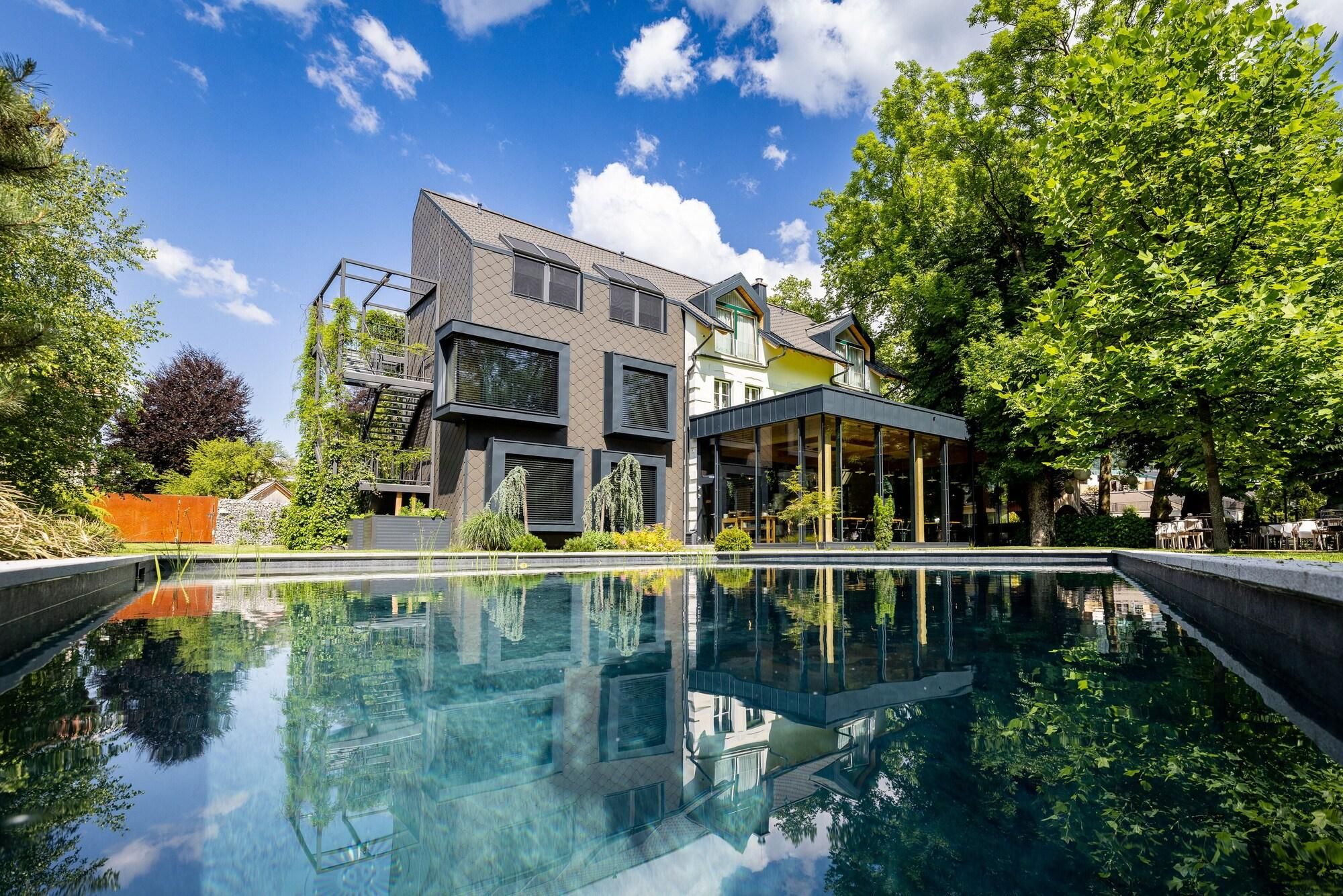 Una casa moderna con piscina, ventanas amplias y jardín.