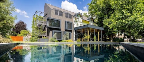A modern house with a swimming pool, large windows, and a garden.