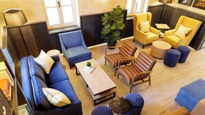 A modern living room with a blue sofa, a wooden coffee table, and yellow armchairs. - Sunrose 7 - Heritage Boutique Hotel - Adults Only (Bohinj)