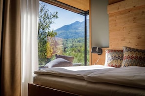 A bedroom with a large window, a bed, and a wooden headboard. - Sunrose 7 Heritage Boutique Hotel (Bohinj)