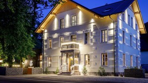 A multi-story building with a symmetrical facade, large windows, and a prominent entrance with a balcony. - Sunrose 7 - Heritage Boutique Hotel - Adults Only (Bohinj)