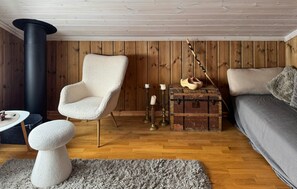 A cozy room with a wooden floor, a fluffy armchair, a vintage trunk, and a modern sofa. - Gorgeous home in Sjusjøen with WiFi (Sjusjøen)