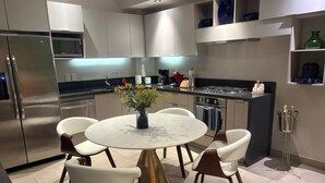 Eine moderne Küche mit einem runden Esstisch, weißen Stühlen und einer Blumenvase.