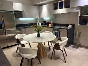 A modern kitchen with a round dining table, white chairs, and a vase of flowers. - Modern and comfortable apartment in the best location in Zona Romantica! (Puerto Vallarta)