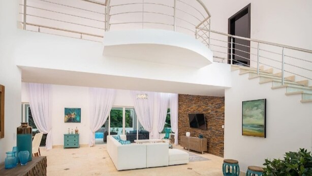 Un vaste espace de vie doté d’un plafond cintré, d’un escalier et d’un mur en pierre.