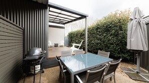 Un patio exterior con una mesa, sillas, una parrilla y una zona de estar cubierta.