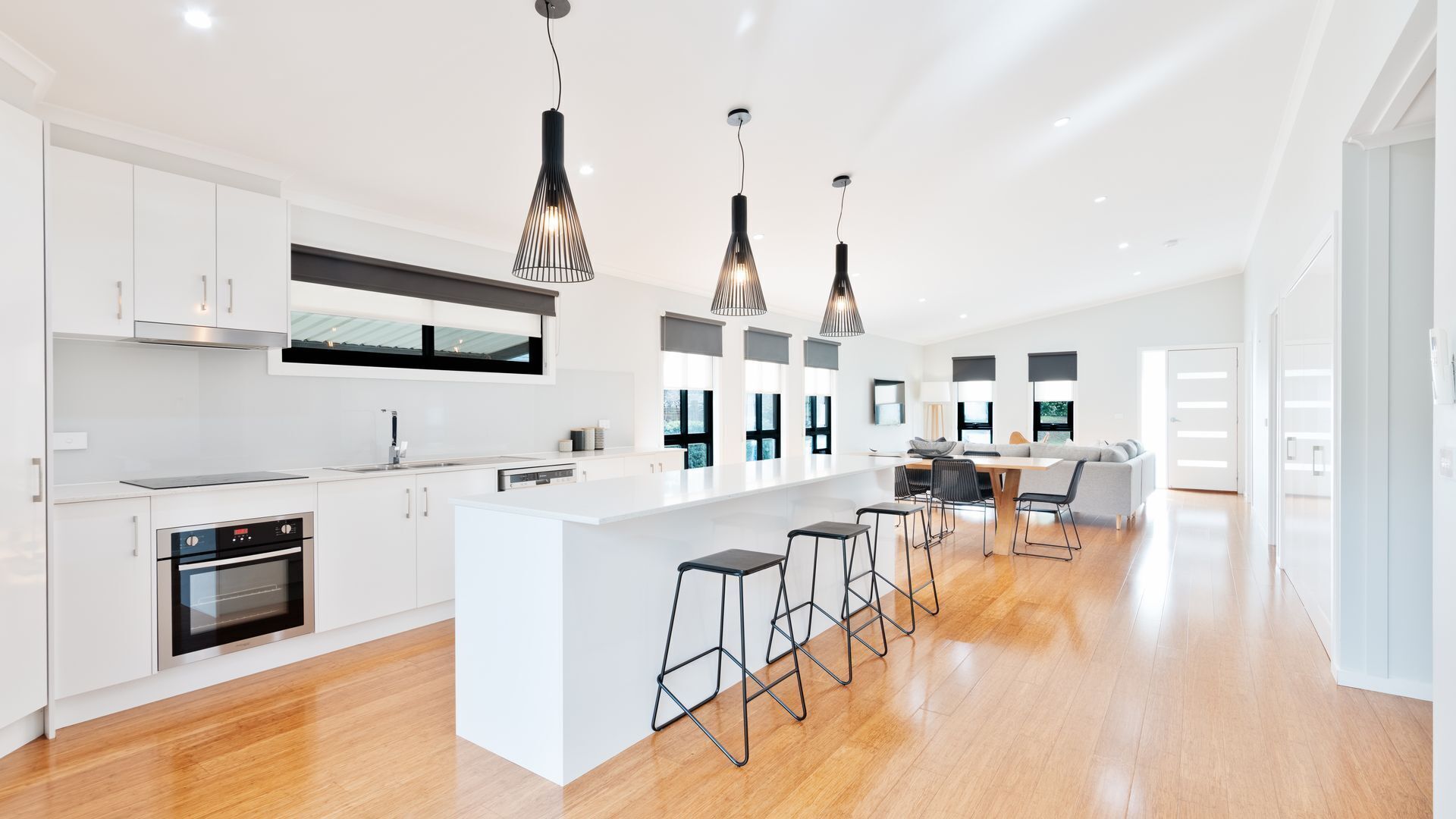 A modern kitchen with white cabinetry, a central island with bar stools, and pendant lighting.