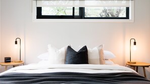 A bedroom with a bed, pillows, a bedside table, a lamp, and a window. - Snowgum Bright 1 - 3 Bedroom, 3 Bathroom (Bright)