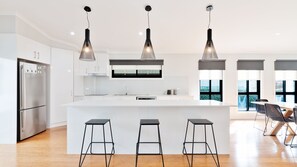 Una cocina moderna con una isla central, taburetes de bar e iluminación colgante.