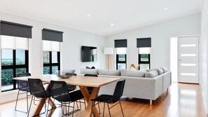 Ein modernes Wohnzimmer mit einer Couch, einem Esstisch mit Stühlen und einem an der Wand befestigten Fernseher.