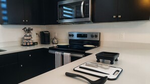 Una cocina moderna con gabinetes negros, una estufa de acero inoxidable, un microondas y una zona de café.