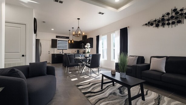 Una sala moderna con un sofá, una mesa de centro y un comedor con sillas y una mesa.