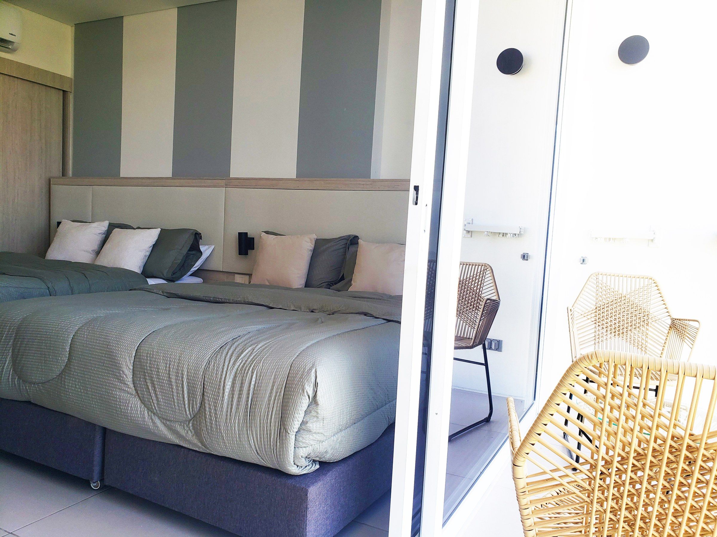 Un dormitorio con una cama grande, cabecera y una silla de mimbre.