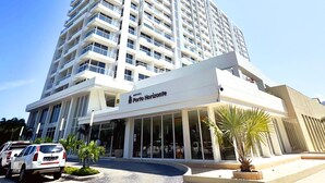 Een modern hotelgebouw met een opvallende entree en een bord waarop ‘Hotel Porto Horizonte’ staat.