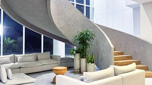 Een modern interieur met een gebogen trap, een hoekbank en potplanten.
