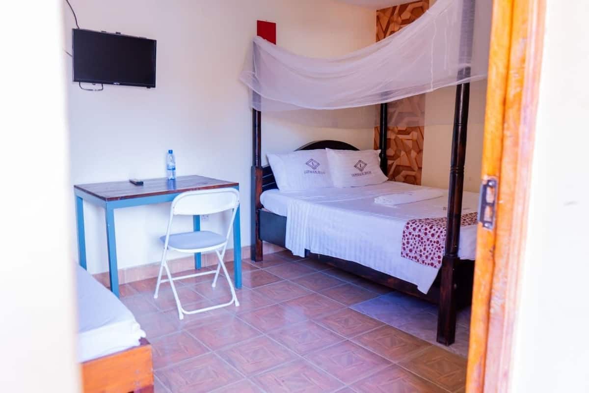 Una habitación con cama, escritorio, silla y televisión.