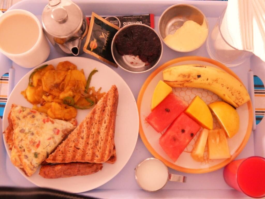 Una bandeja con un plato de comida que incluye tostadas, un tazón de sopa y una fuente de fruta.