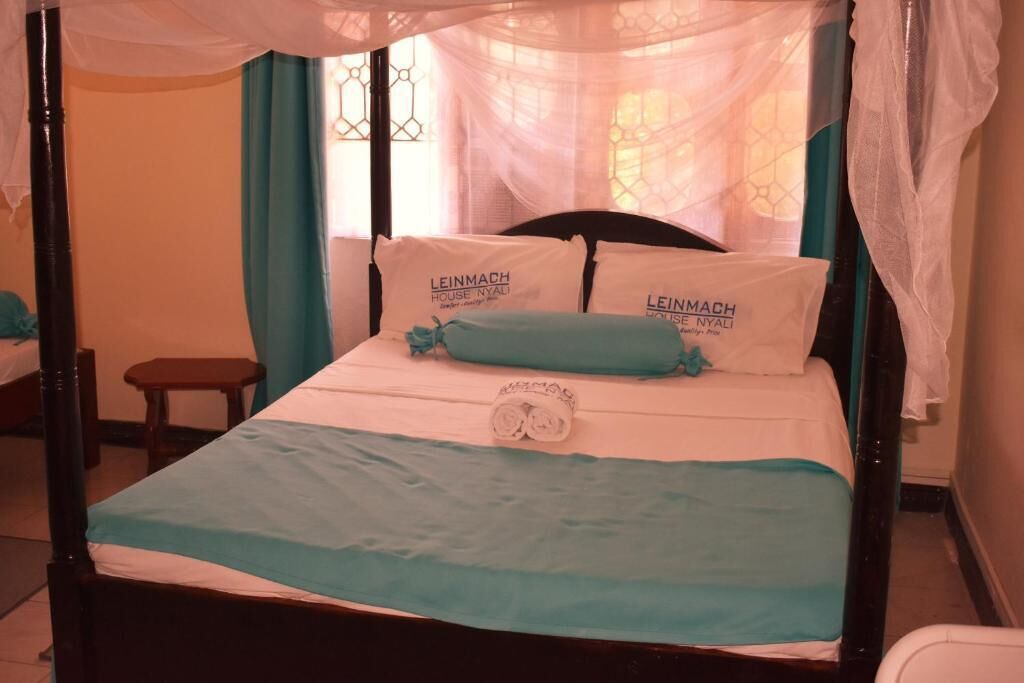 A four-poster bed with a canopy, white linens, and teal accents.