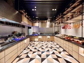 A modern kitchen with geometric patterned flooring, stainless steel appliances, and a variety of food items displayed on shelves. - Dhawa Xi'an Chanba (Xi'an)