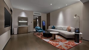 A modern living room with a sofa, a blue armchair, a coffee table, and a TV mounted on the wall. - Dhawa Xi'an Chanba (Xi'an)