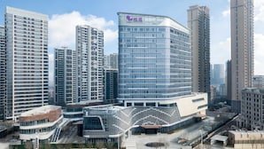 A modern hotel with a curved glass facade, surrounded by high-rise buildings. - Dhawa Xi'an Chanba (Xi'an)