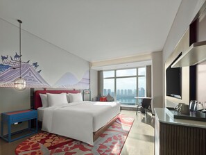 A modern hotel room with a large bed, a desk, a chair, and a view of the city skyline. - Dhawa Xi'an Chanba (Xi'an)